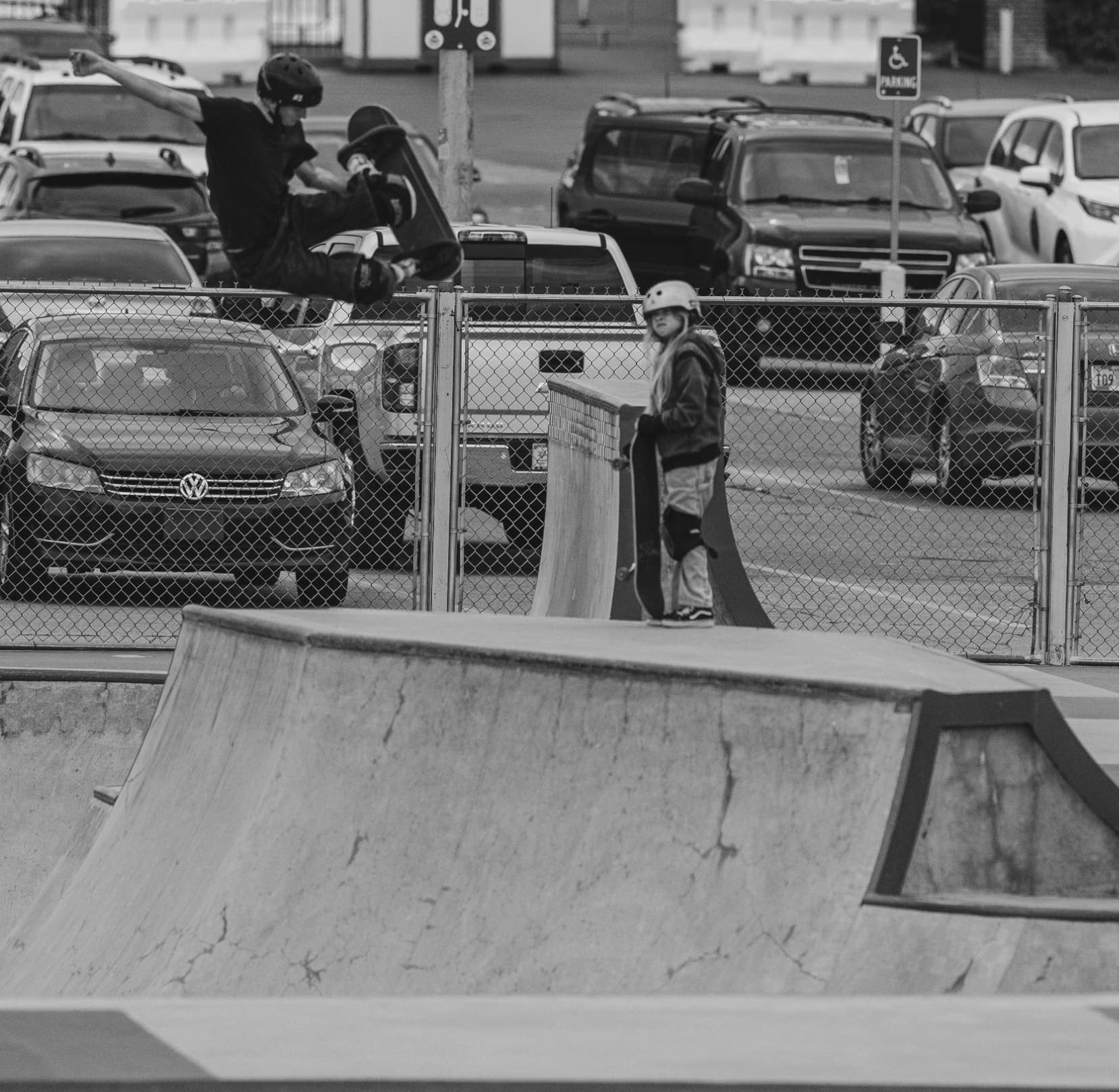 A young skater watching a trick at the park, board in hand